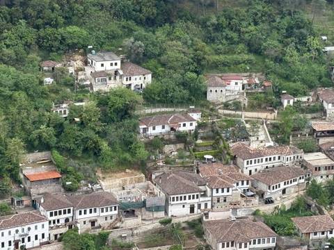       Aerial view of tree-covered hills dotted with traditional white stone houses and terraced gardens.
  