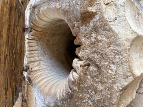       Close-up of an ancient carved stone well or basin showing weathered textures and a metal peg
  