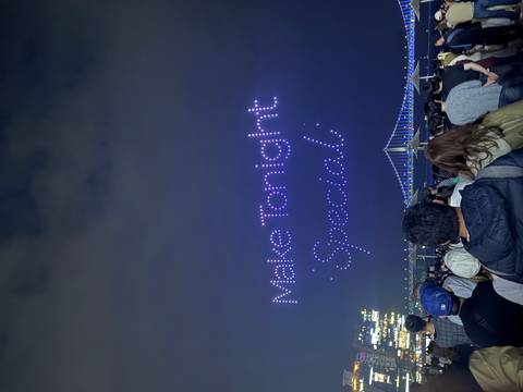       Nighttime drone light show spelling 'Make Tonight Special' above an illuminated suspension bridge and large crowd.
  