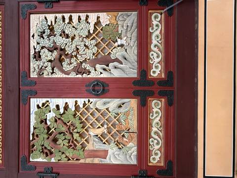       Intricately carved and painted wooden temple doors featuring trees, clouds and lattice patterns.
  