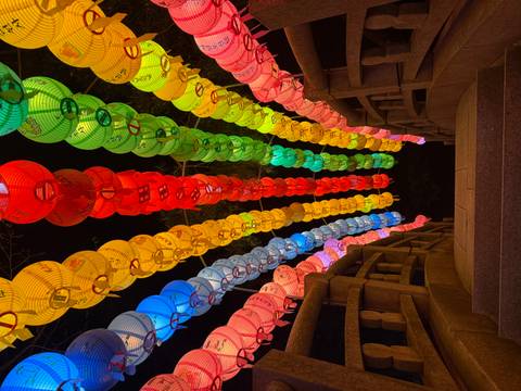       Vibrant rainbow lantern tunnel illuminated at night during a Korean festival.
  