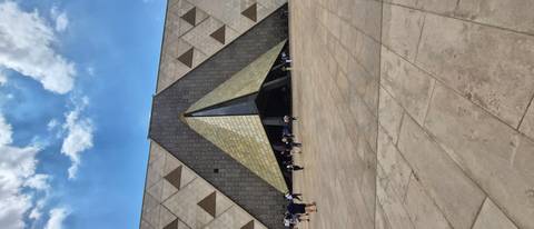       Visitors walk across the vast plaza of Egypt’s new Grand Museum with modern pyramid entrance.
  