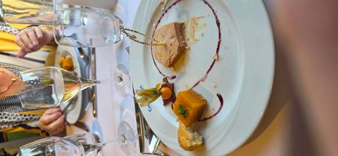       Partially eaten foie gras plate with wine glasses and elegant garnish.
  