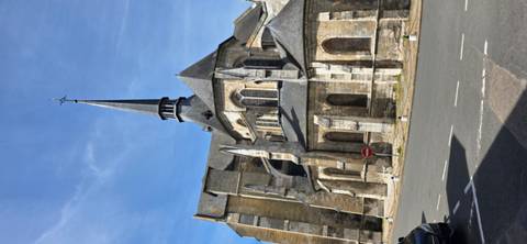       Angled view of stone church spire against clear blue sky.
  