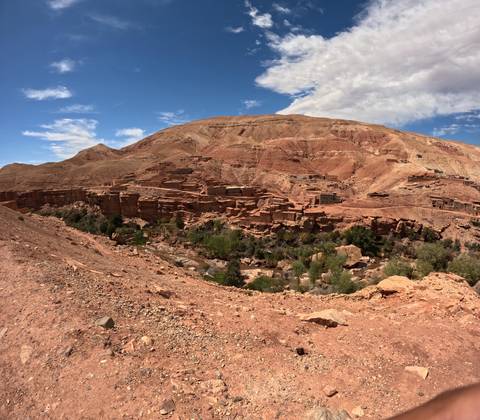       Panoramic view of abandoned adobe cliff village under bright sky.
  