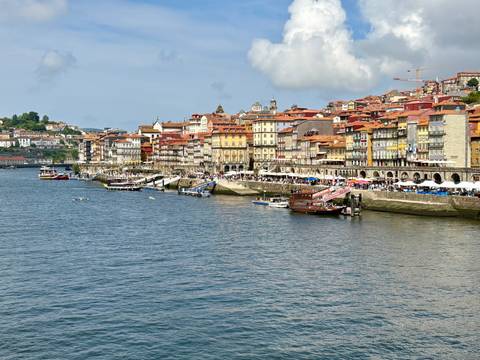       Colorful Ribeira waterfront houses lining the Douro River in Porto with tour boats docked below.
  