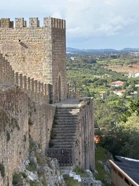       Stone stairway along the fortified medieval walls of Óbidos overlooking green countryside.
  