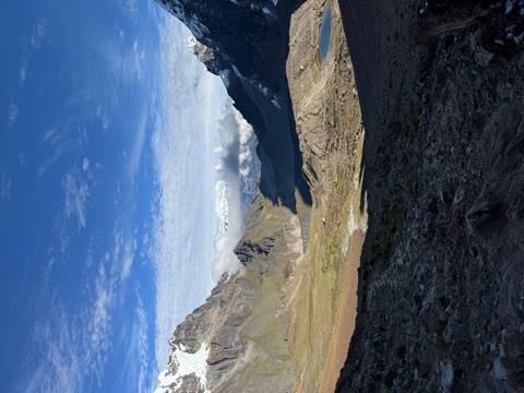       Expansive high-altitude valley with distant snowy peaks under a bright sky.
  