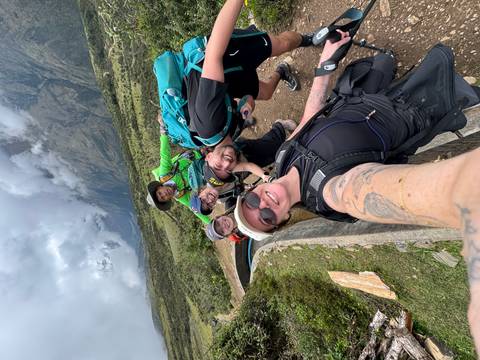       Cheerful group selfie of trekkers with misty mountains behind them.
  
