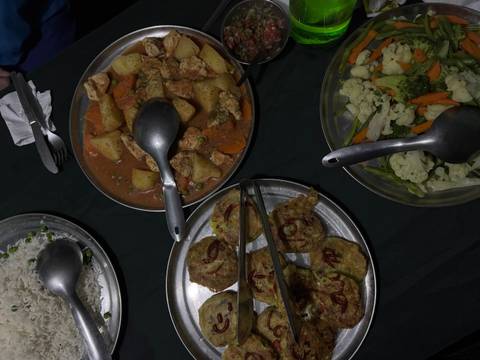       Evening meal of rice, vegetables and stew served on metal plates in camp.
  