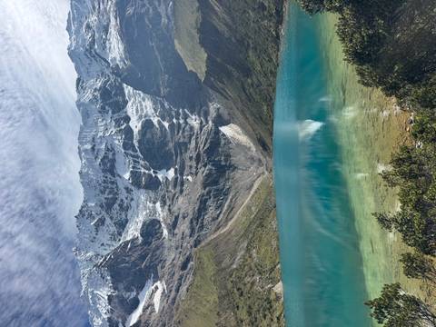       Turquoise alpine lake mirroring dramatic glacier wall beneath patterned sky.
  