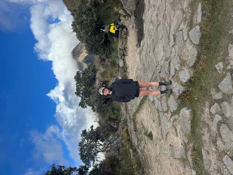       Solo traveler standing on stone paving with cloud-shrouded peak in background.
  