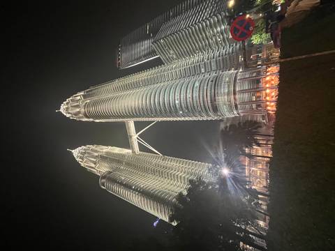      Night view looking up at the illuminated Petronas Twin Towers connected by a skybridge.
  