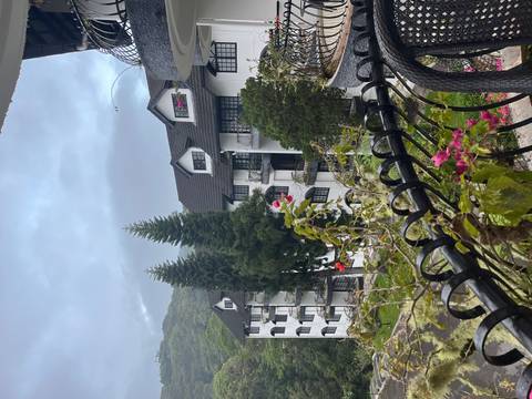       Tudor-style white hotel buildings amid green hills and pine trees in the Cameron Highlands.
  
