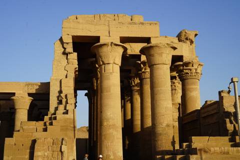       Side view of massive stone columns and capitals at Kom Ombo Temple glowing in late afternoon light.
  
