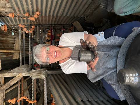       Traveler inside a pottery workshop proudly showing a freshly made clay cup on the wheel.
  