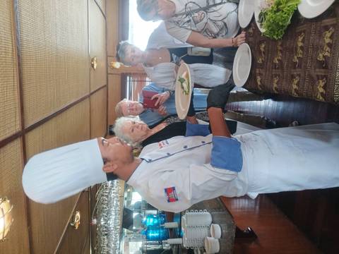       Cruise ship chef presents plated dish to attentive passengers during cooking demo.
  