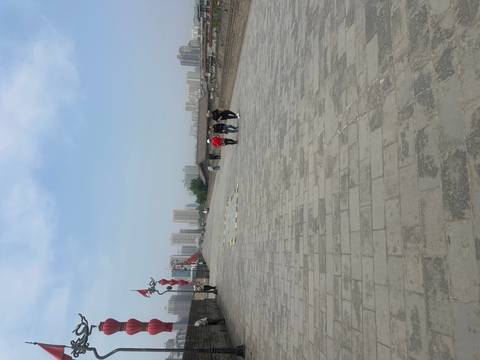       Visitors stroll along the broad stone ramparts of Xi'an's ancient city wall with modern high-rises beyond.
  