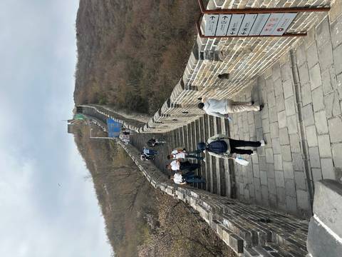       Visitors climbing a steep stone stairway on the Great Wall of China up a hillside ridge
  