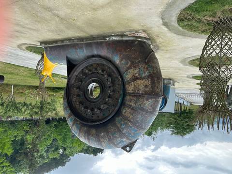       Large artistic sculpture resembling a rusted spiral turbine with yellow snail accent in an outdoor park
  