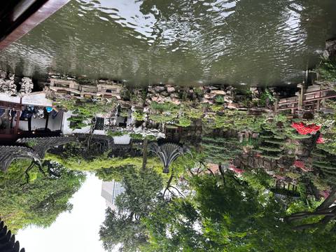       Classical Chinese garden with ornate pavilions, rockeries and a pond surrounded by flowering shrubs
  