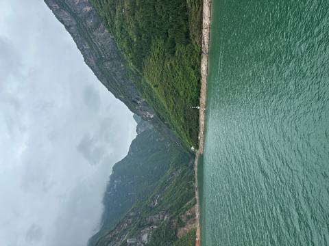       Green river winding through high mountains with a lone lighthouse on the shore
  
