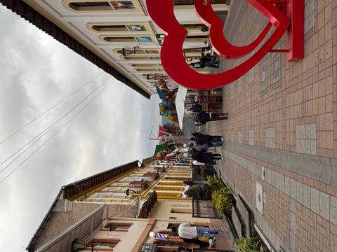       Cobbled colonial street with yellow and white buildings and a large red heart sculpture at dusk.
  