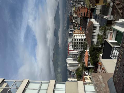       Panoramic view over a modern city with Andean mountains rising behind and low clouds skimming the peaks.
  