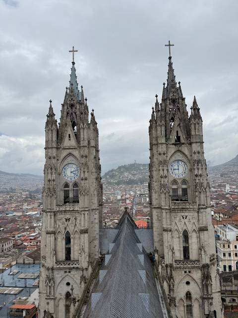       Twin clock towers of a neo-Gothic basilica rise above the cityscape panorama.
  