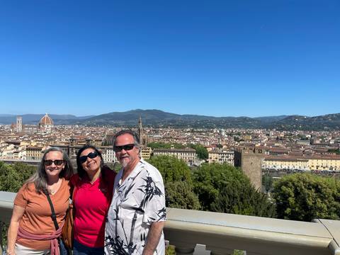       Three travelers with panoramic view over Florence including the cathedral dome and rooftops.
  