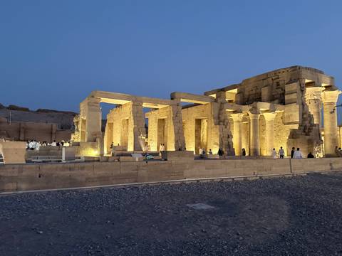       Kom Ombo Temple beautifully lit at dusk with visitors exploring the ancient columns.
  