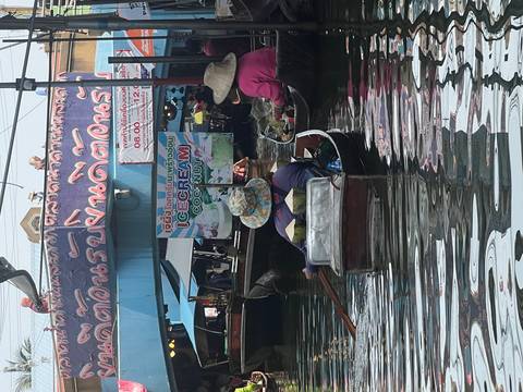       Small wooden boats crowd a canal at Damnoen Saduak Floating Market, one selling coconut ice cream.
  