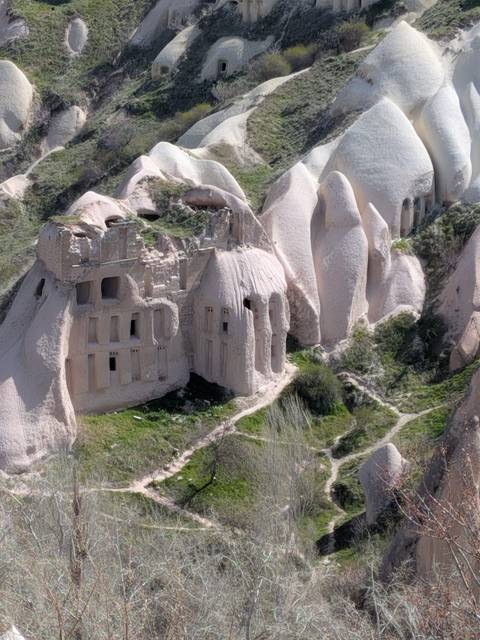       Eroded pink-beige rock formations in Cappadocia reveal ancient cave dwellings carved into the cliffs.
  