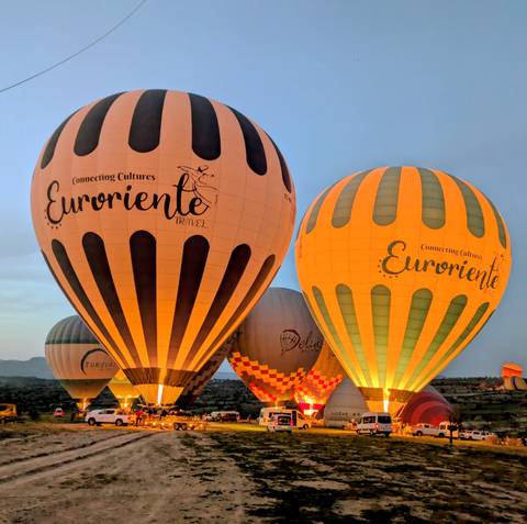       Illuminated hot-air balloons prepare for lift-off in Cappadocia during the early dawn light.
  