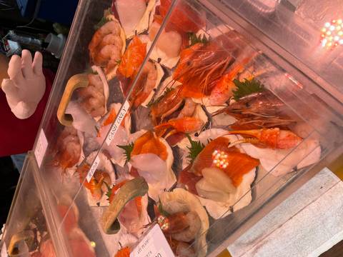       Display of fresh sashimi and prawns on ice at a Japanese seafood market stall
  