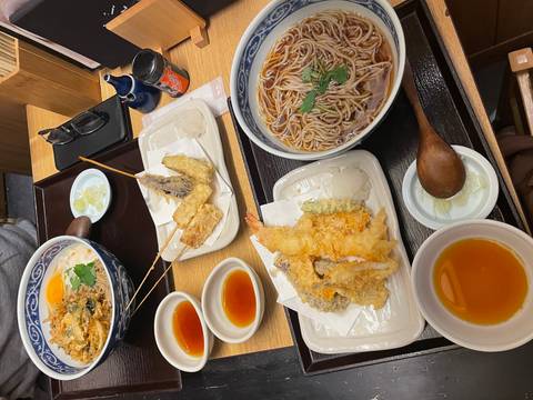       Traditional Japanese meal featuring tempura, soba noodles and dipping sauces neatly arranged on wooden trays
  