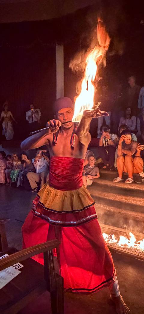       Fire dancer performs at night before an audience capturing the moment with phones.
  