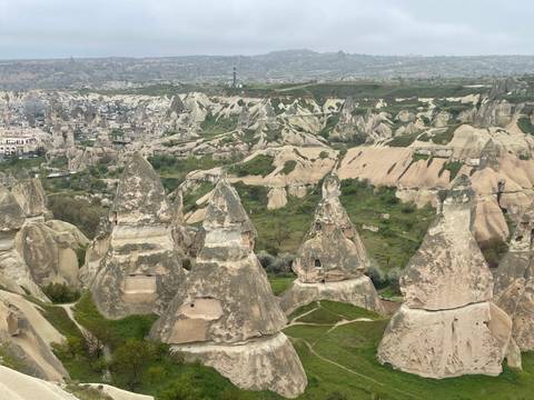       Panoramic vista of Cappadocia's fairy chimneys and distant town under hazy sky
  