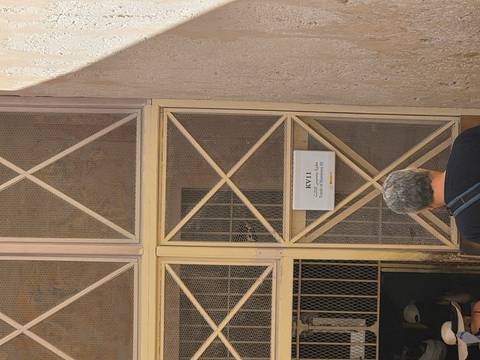       Visitor stands at mesh-covered entrance KV11 in the Valley of the Kings beneath a simple sign.
  