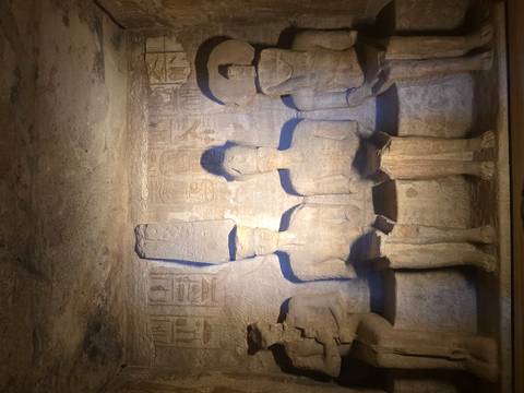       Four seated stone gods are softly lit within the inner sanctuary of Abu Simbel.
  