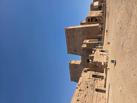       Philae Temple’s pylons and courtyards stand amid a sandy landscape with scattered visitors.
  