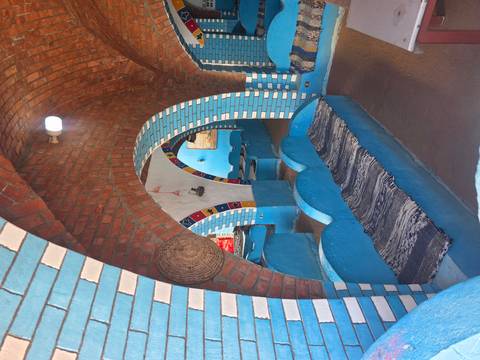       Colourful interior of a Nubian-style restaurant or cafe with blue benches, arched brick ceilings and decorative tiles.
  