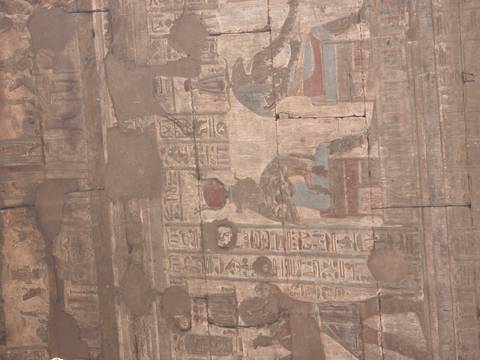       Ancient painted mural with faded colours and hieroglyphs on cracked wall inside Egyptian temple.
  