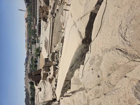       Another angle of unfinished obelisk quarry with sandy floor and distant buildings.
  