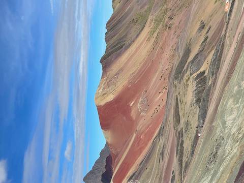      Vibrant red and yellow slopes of Rainbow Mountain under a blue sky
  