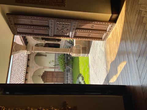       Sunlit colonial courtyard seen through an ornately carved wooden doorway
  