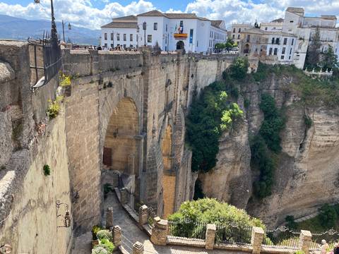       Dramatic view of Puente Nuevo bridging a deep gorge with whitewashed buildings perched atop cliffs in Ronda.
  