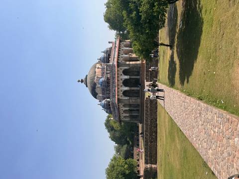       Domed Isa Khan’s Tomb stands at the end of a stone path amid green lawns in Delhi.
  