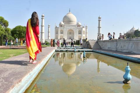       Iconic Taj Mahal reflected in a long pool as visitors explore the marble terrace.
  