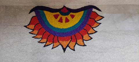       Colorful flower-shaped rangoli art created with powdered pigments on marble floor
  